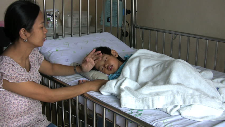 A concerned young mother checks on her sick little boy in the hospital.