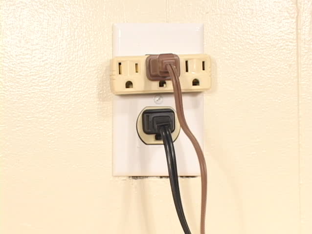 Too many electrical cables are plugged into one outlet in a shot symbolizing the overuse of energy.