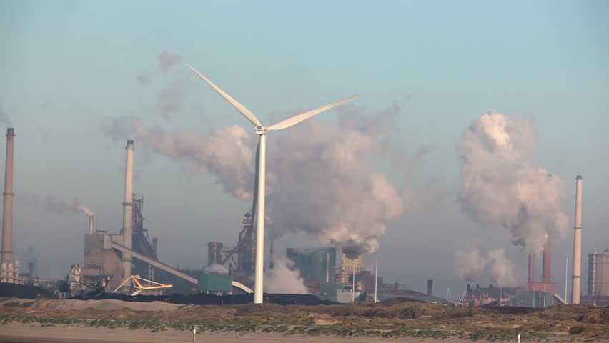 Wind turbine with big smokestacks in the background