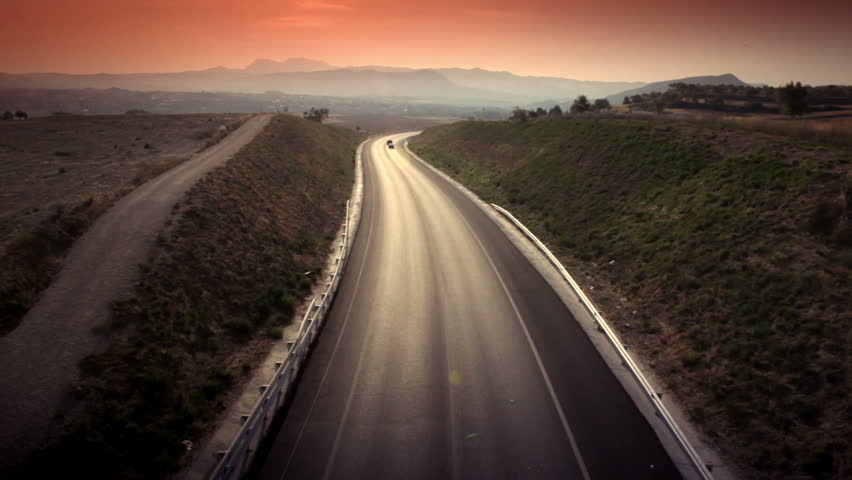 Aerial shot of car passing on the highway to the mountains