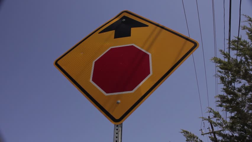 Yellow stop ahead sign on country road, power lines in background low angle