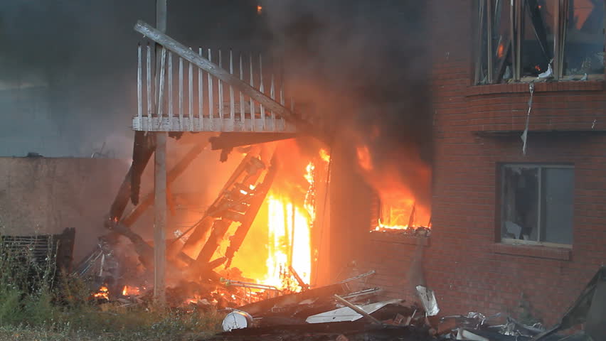 House on fire after sunset. Basement brick wall and patio in full flames and smoke. Total loss and destruction.