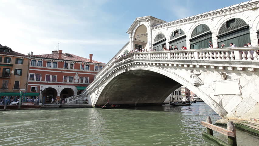 Historical ancient Grand Canal in Venice Italy. Tourists cross Rialto Bridge. Only means of transportation is by boat. Tourism helps in poor economy.