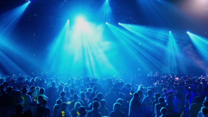 Many people at rave party, crowd dance in blue light of projectors