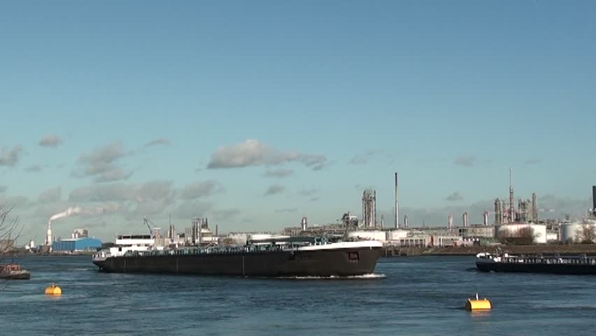 oil tanker in harbor of Rotterdam Netherlands passing by big petrochemical refinery