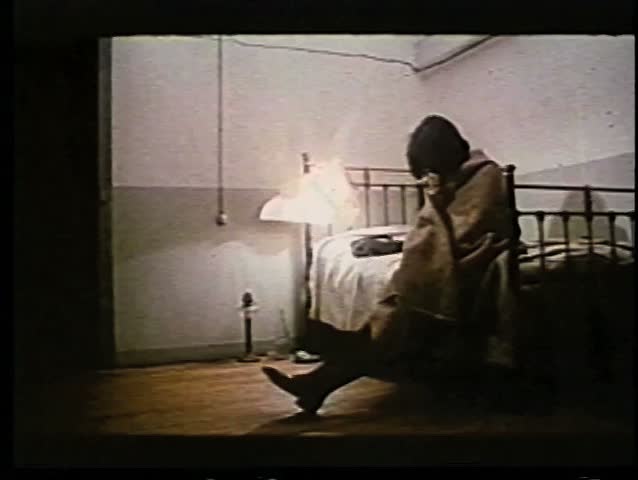 Woman wrapped in blanket sitting on bed smoking