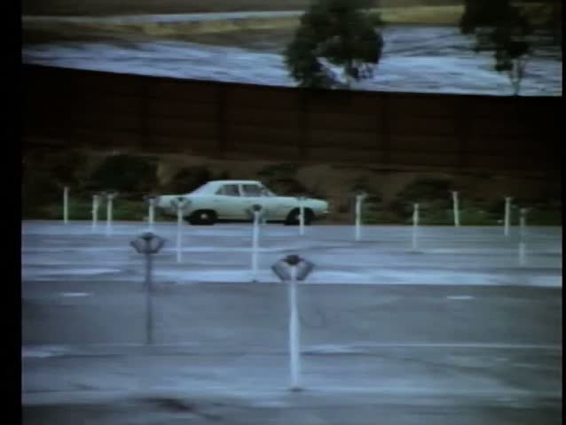 1970s car driving along empty drive-in