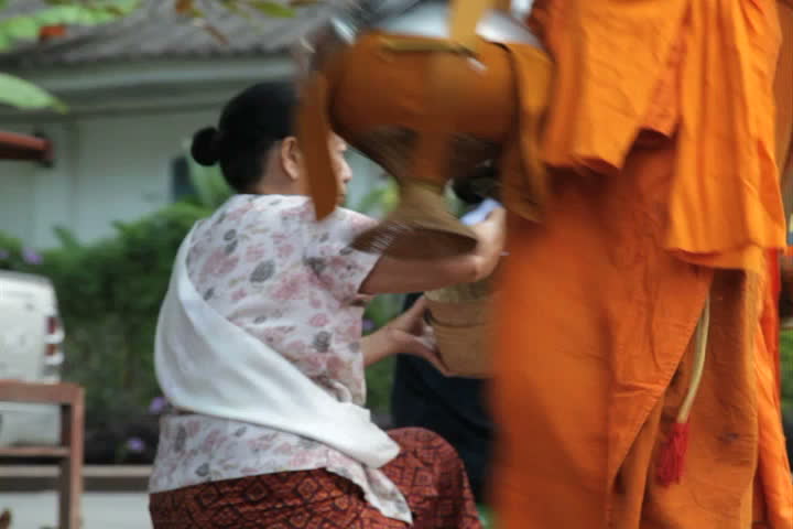 LUANG PRABANG, LAOS - OCTOBER 27: Two women give sticky rice to monks during the morning procession in Luang Prabang, Laos on October 27, 2011.