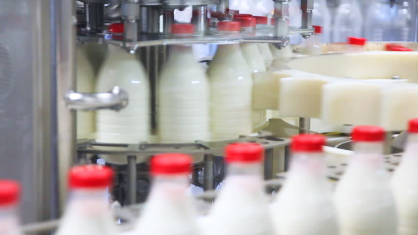 fresh milk poured into bottles, screwed red caps and send to consumers, very close