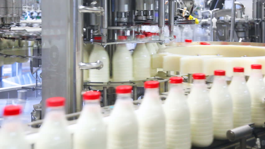 fresh milk poured into bottles, screwed red caps and send to consumers, close-up