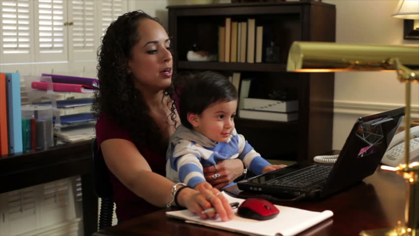 A pretty Hispanic work-at-home mom holds her son while taking a phone call.