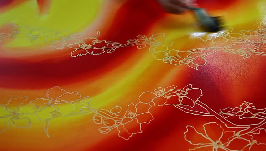 An artist paint a base red & yellow color on beautiful batik fabric with flower motif