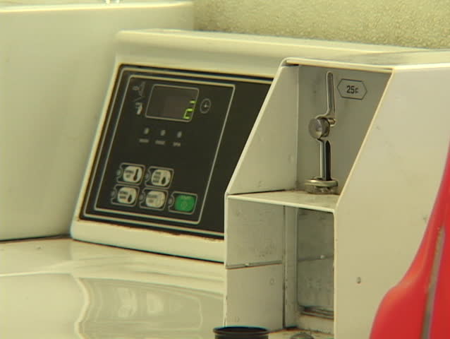 A woman does a load of laundry in a Laundromat.