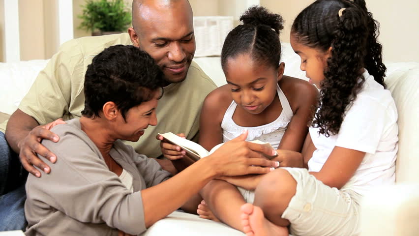 Proud ethnic parents listening to daughter read aloud