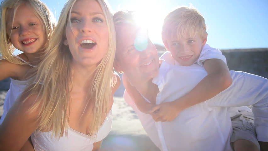 Young blonde caucasian parents having fun with their children on the beach