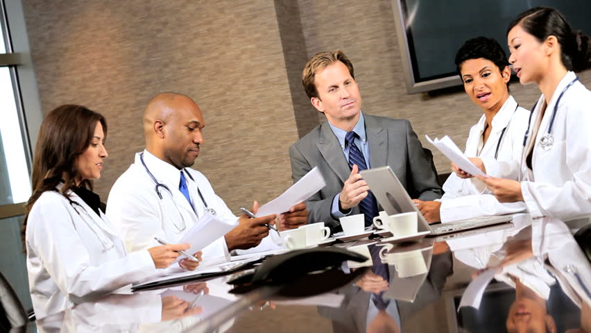 Young multi ethnic medical executives meeting in the boardroom of a modern hospital building