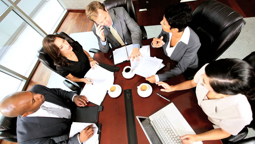 Overhead view of caucasian business executive giving his multi ethnic team news of success