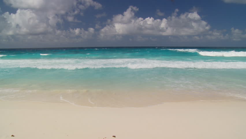 accumulating clouds over waves touching sandy beach