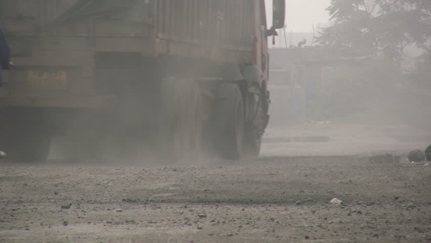 QINGDAO - APRIL 9: A Chinese man cycles on a dusty road behind a truck on April 9, 2010 in Qingdao, China.
