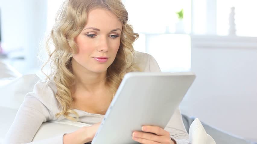Blond woman answering mobilephone while using tablet