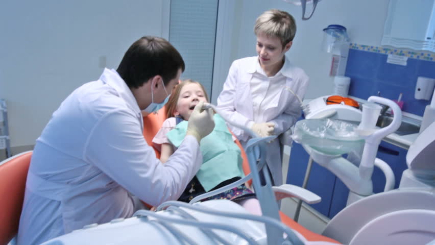 Dentist and his assistant treating a little scared patient 
