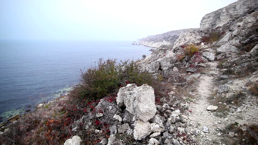 Footpath among old stones at the sea. Autumn