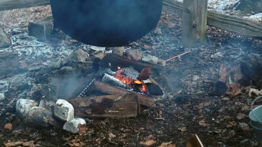 Wood fire under a cauldron filled with maple sap during the annual maple syrup making time in the sugar bush A traditional way of making maple syrup.