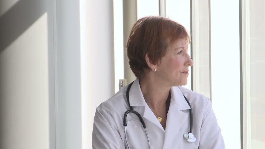 Female doctor looking out the window and turns to camera