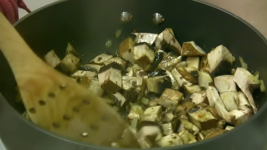 Portobello Mushroom Saute (HD). Portobello Mushroom Saute with moving wooden utensil and olive oil pan. 