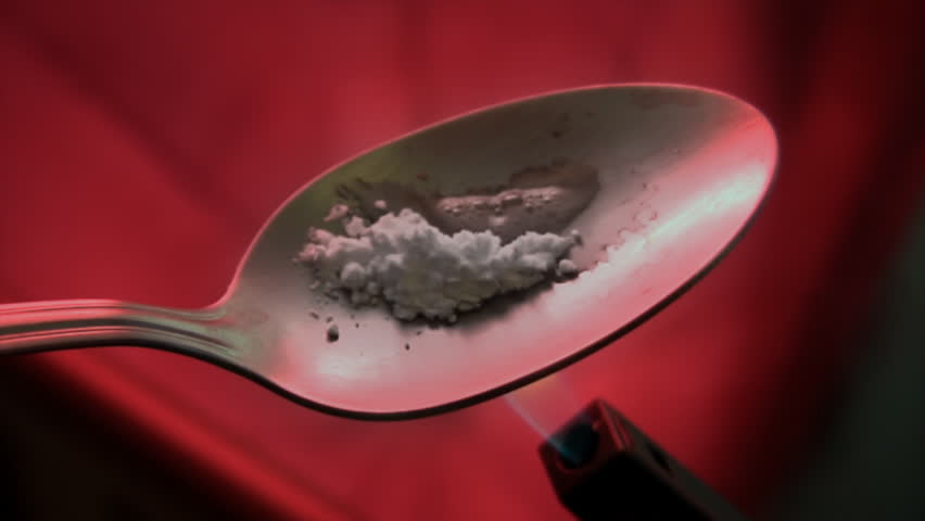 Drug Spoon Heated (HD). Heating a metal spoon seen close up with powdered drug. Used red gel for added dramatic ambient.