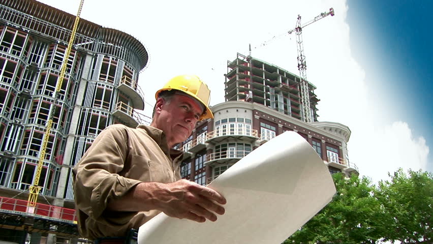 architect looking at building plans, then rolling them up and smiling at the camera.