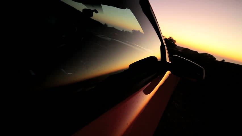 Luxury convertible vehicle parked hillside at sunset