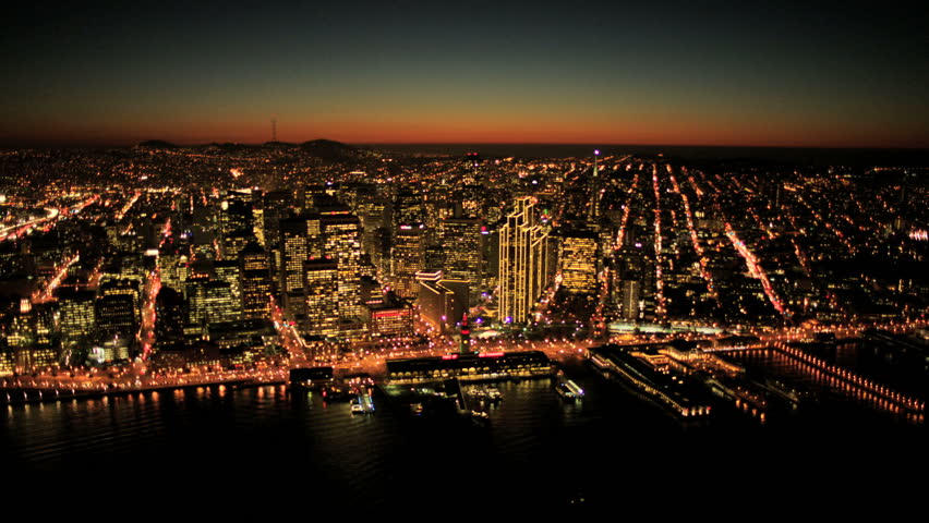 Aerial sunset low angled illuminated view of Fishermans Wharf and San Francisco city skyscrapers, North America, USA