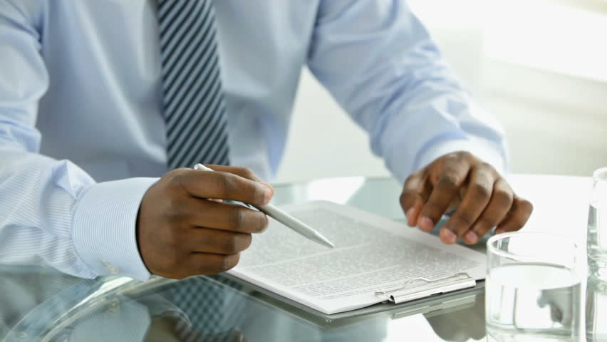 An Afro-American businessman looking through a document attached to a clipboard