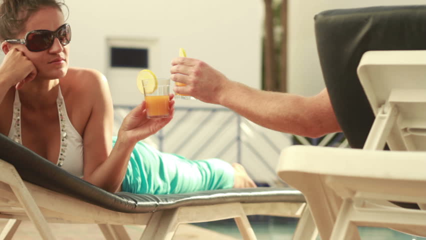 Couple enjoying drinks on sunbeds, outdoors