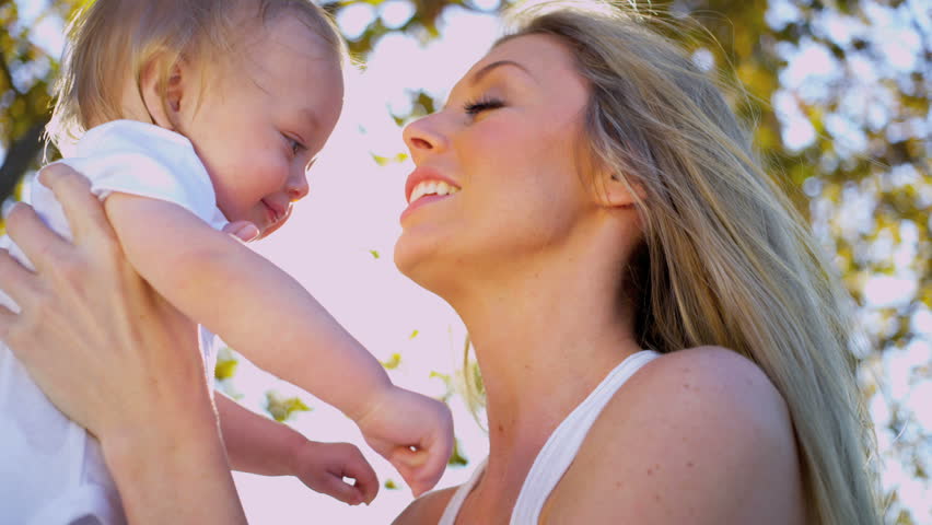Young Caucasian mother holding her baby in the sunshine outdoors