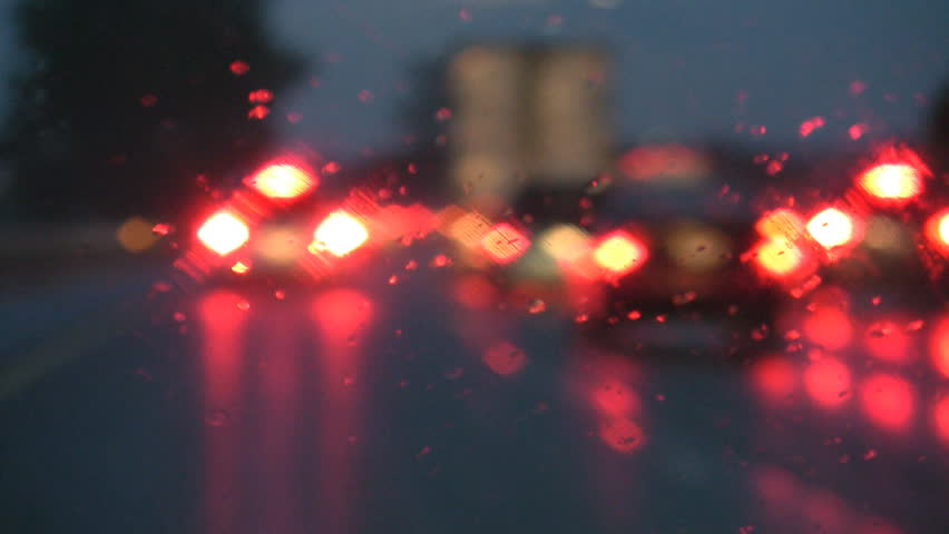 Defocused lights. Driving on a rainy highway, cars braking. Rain on windshield. 