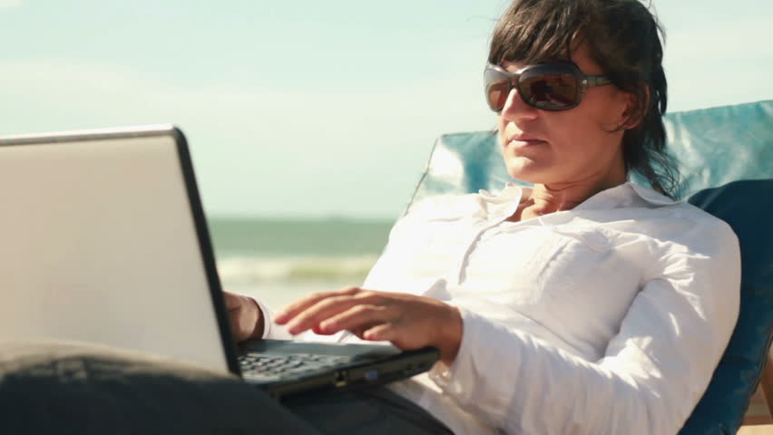 Businesswoman finishing work on laptop and relaxing on sunbed