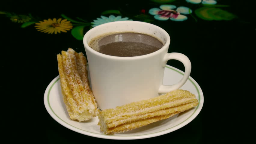 Churros with Hot Cocoa Closer (HD). Sweet fried churros with hot cocoa cup being dipped and eaten with intermediate closer macro shot. Spanish and Mexican delicacy for dessert. 