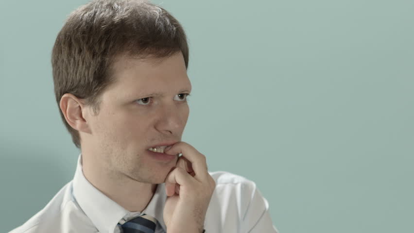 Stressed mid adult businessman biting fingernails, blue background. Copy space