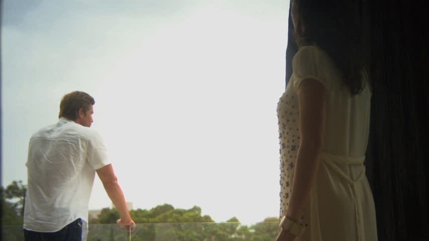 MEDIUM SHOT OF A WOMAN WALKING ONTO A BALCONY TO MEET HER HUSBAND