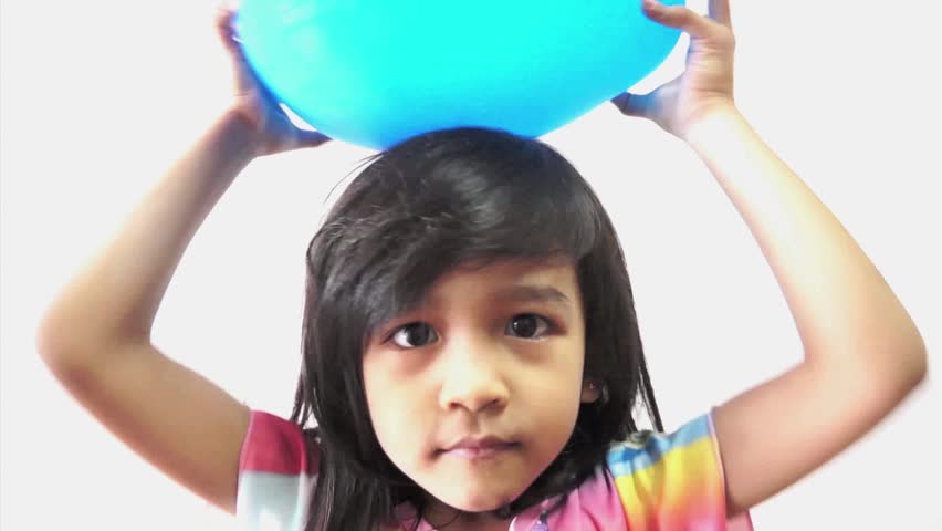 Young and cute girl experimenting and rubbing balloon to her hair to get the electrostatic effect.