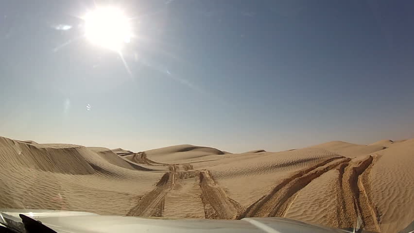View through window of car driving through sand dunes in Sahara Desert