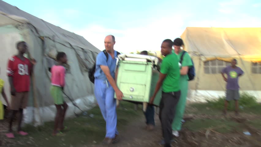 PORT-AU-PRINCE - CIRCA OCTOBER 2010: Medical volunteers load exam table in a tent city in Port-au-Prince, Haiti circa October 2010.