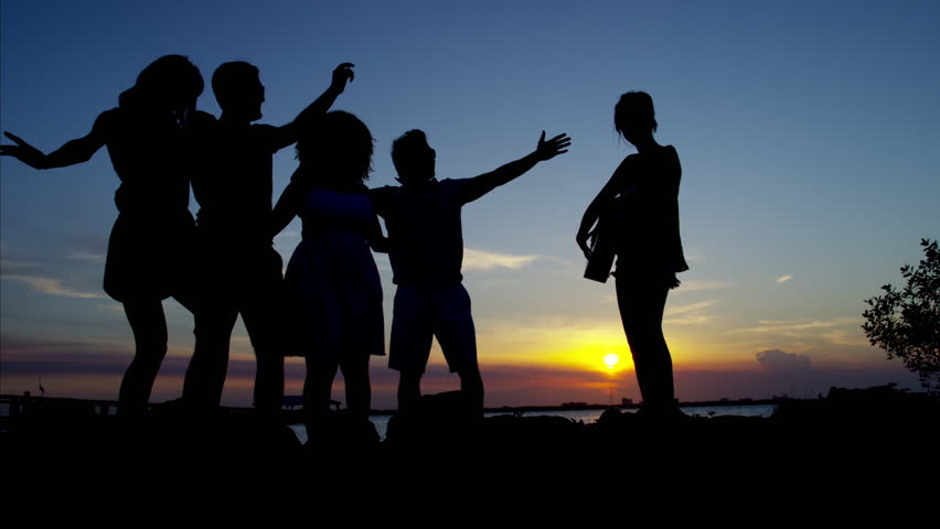 Happy 3 Friends Silhouettes Having Fun At Dusk On Top Of The Mountain 