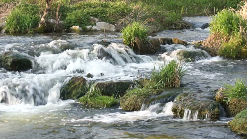 	Close up of water flowing vividly over stones in a brookbed