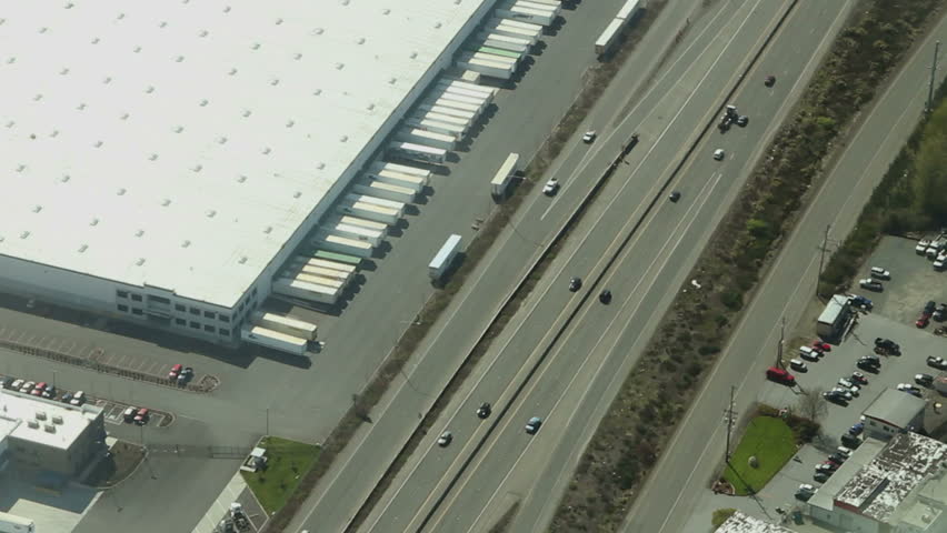 Low-level aerial view following interstate through manufacturing area
