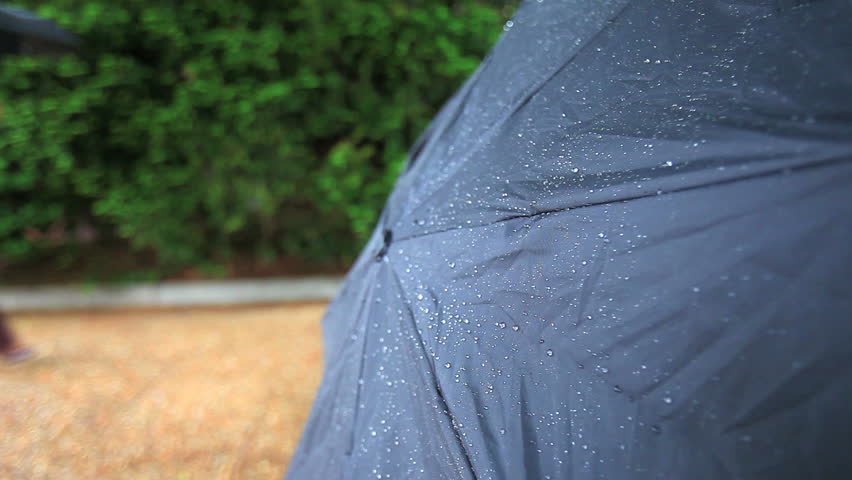 beaded rain on umbrella with person walking by with umbrella up