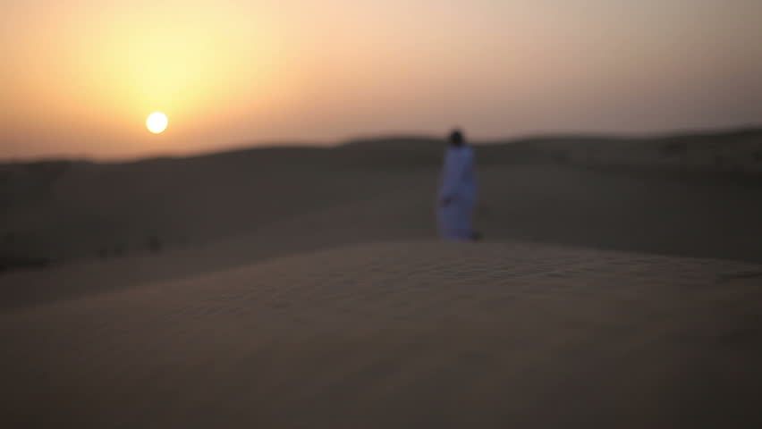 Weary man goes in the desert at sunset