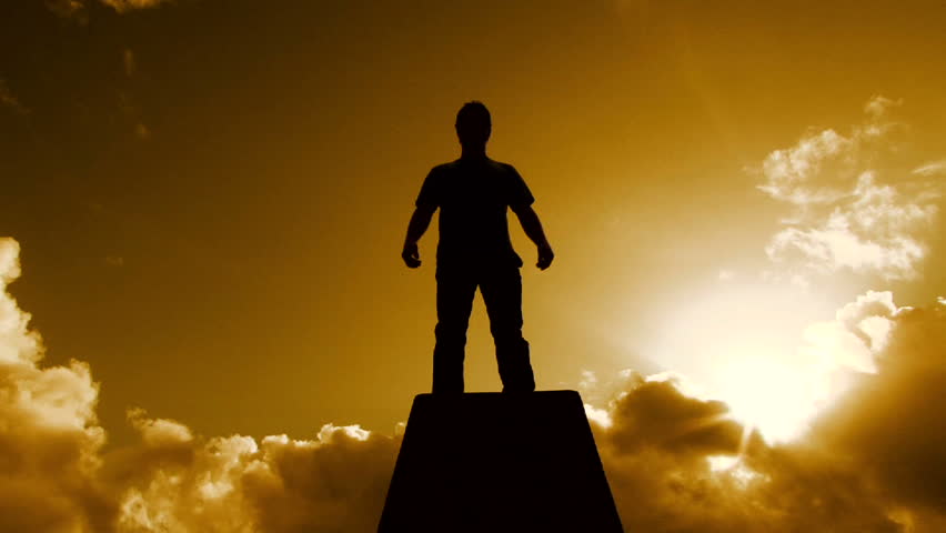 Beautiful warm cloudscape with man silhouetted standing atop pedestal structure looking out among the sky. Full HD 1920 x 1080.